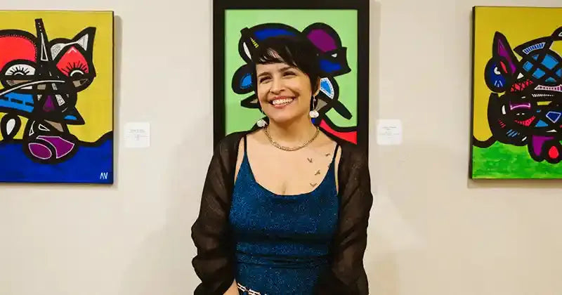 rtist Ayiana Viviana standing in front of her vibrant abstract paintings at an exhibition, smiling confidently. Contemporary statement pieces with bold colors and intricate designs.