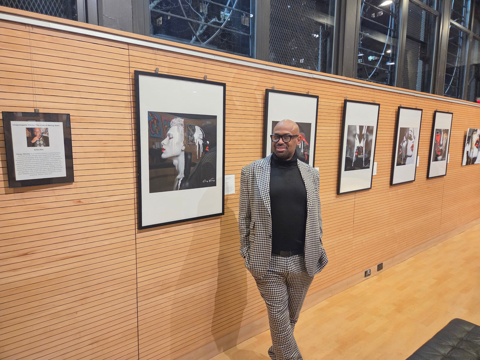 Corey Wesley standing alongside one of the featured works from the Unapologetic Faces series during the opening of his debut exhibition in New York City.