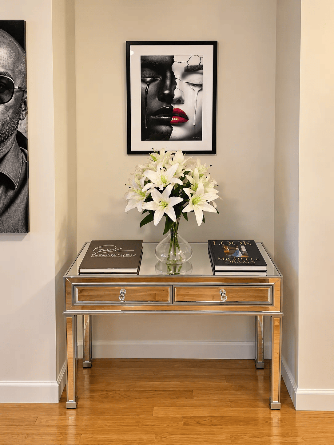 Broadway Duality by Corey Wesley, framed, above a mirrored console table with white lilies.