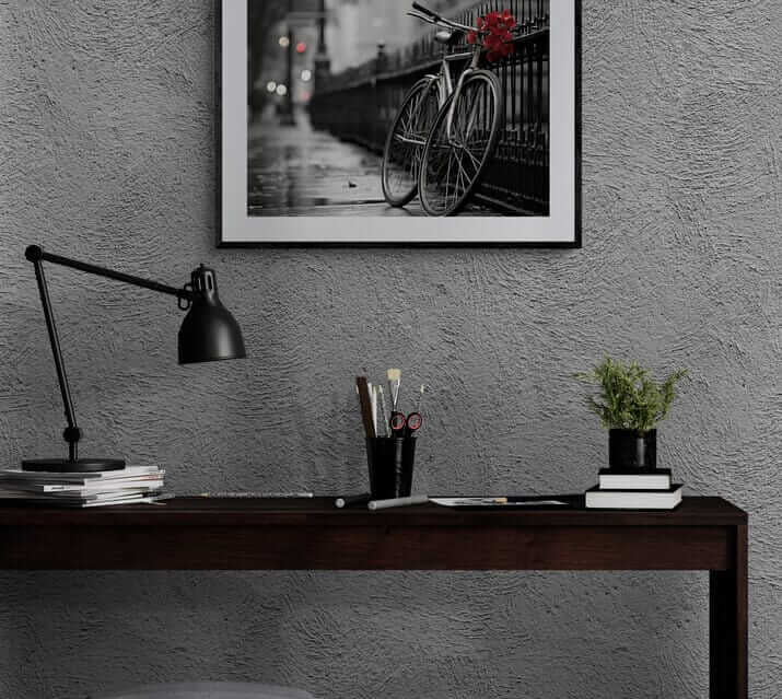 Red Floral Bicycle Print in black frame on gray wall above dark wood desk with black lamp and potted plant, modern African-American art