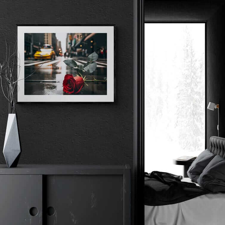 Framed poster of a red rose on a rainy NYC street, displayed on a dark wall in a modern bedroom, promoting Afrocentric home decor and colorful wall art.