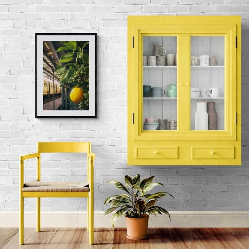 NYC Lemon Tree kitchen art framed print in modern decor setting with yellow chair and cabinet against white brick wall.